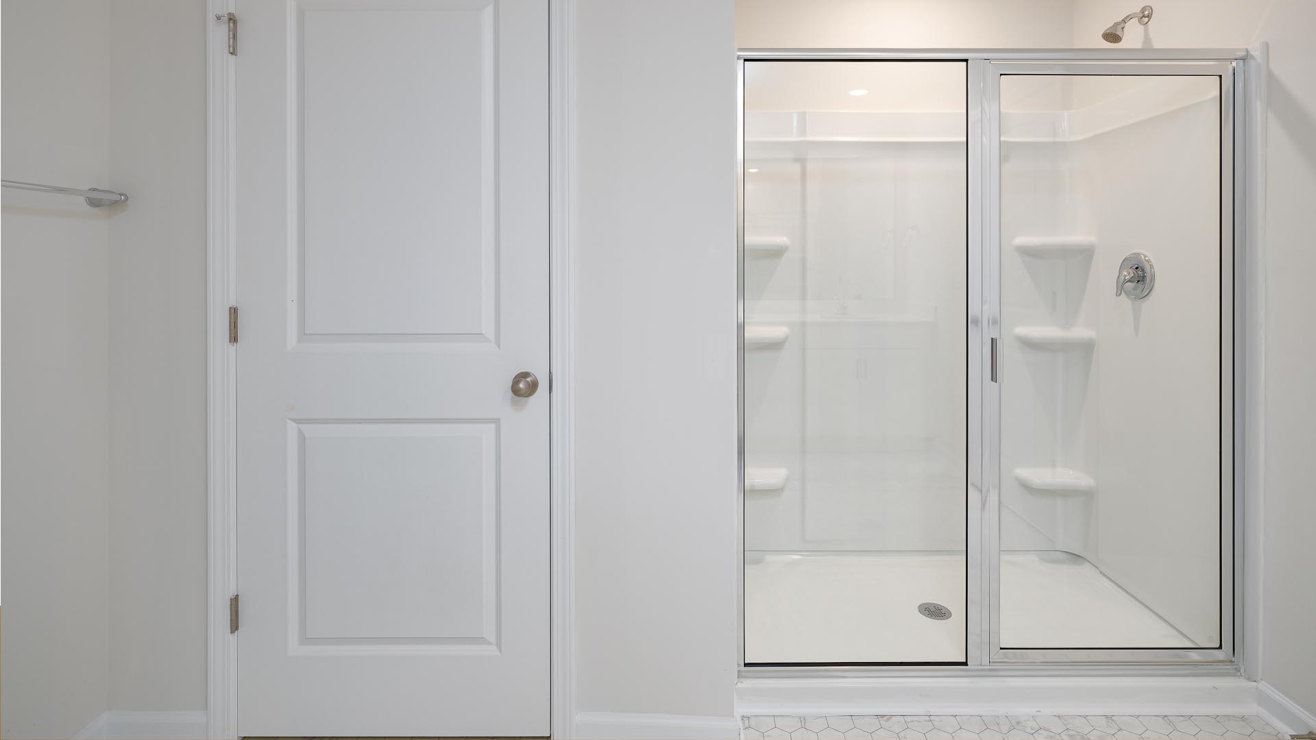 Primary bathroom with double sink vanity, white cabinets, and standing glass door shower