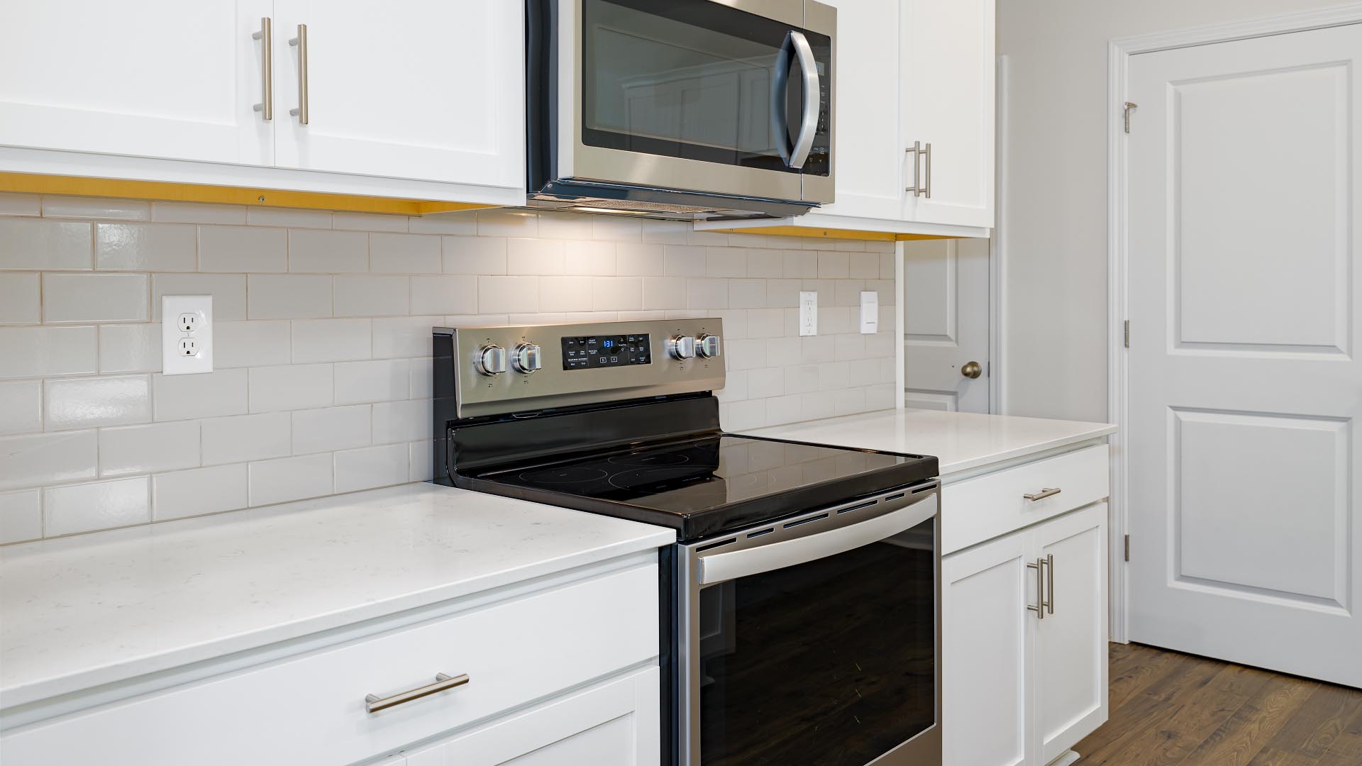 Kitchen and island with white cabinets, countertops, and stainless steel appliances