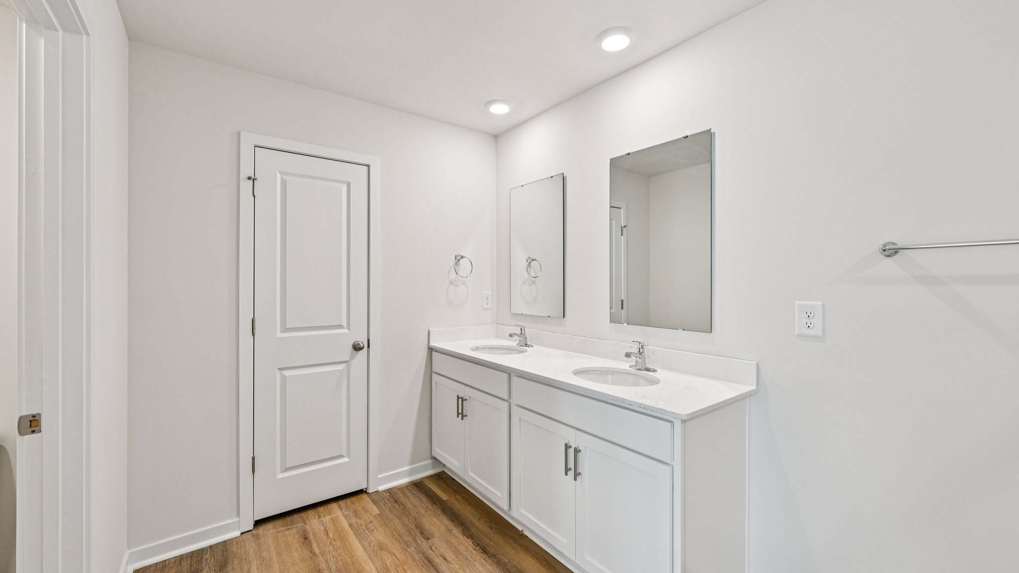 Primary bathroom with double sinks, white cabinets and glass door shower
