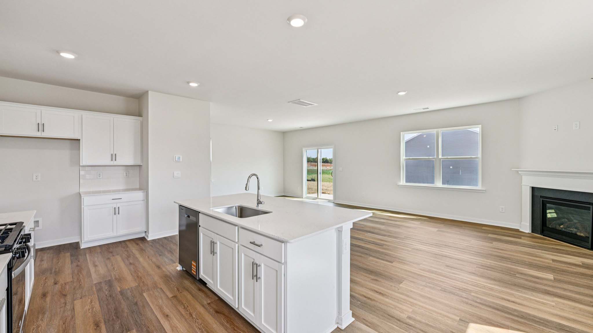 Kitchen and island with white cabinets, white subway tile backsplash and stainless steel appliances