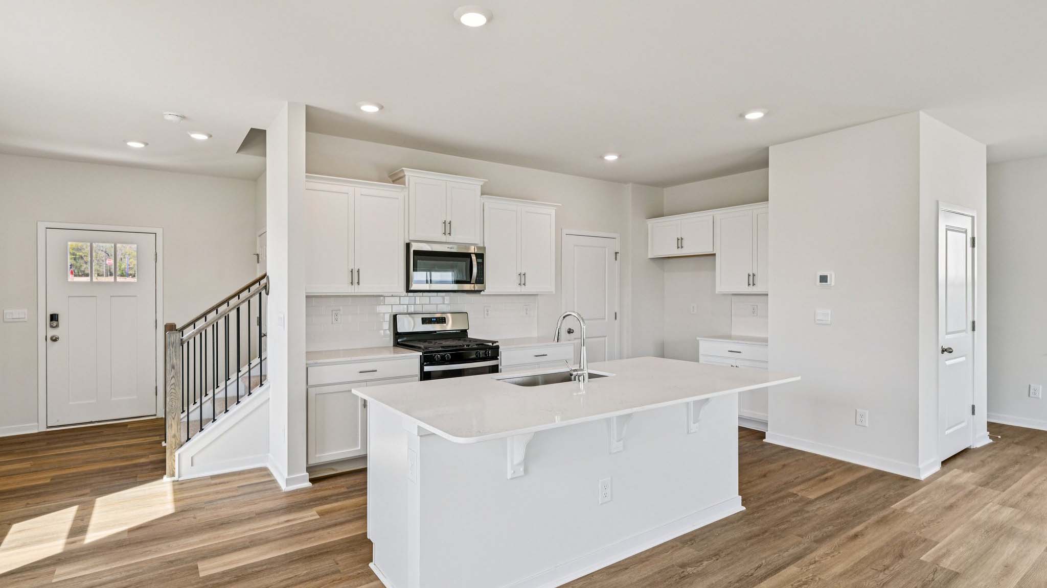 Kitchen and island with white cabinets, white subway tile backsplash and stainless steel appliances