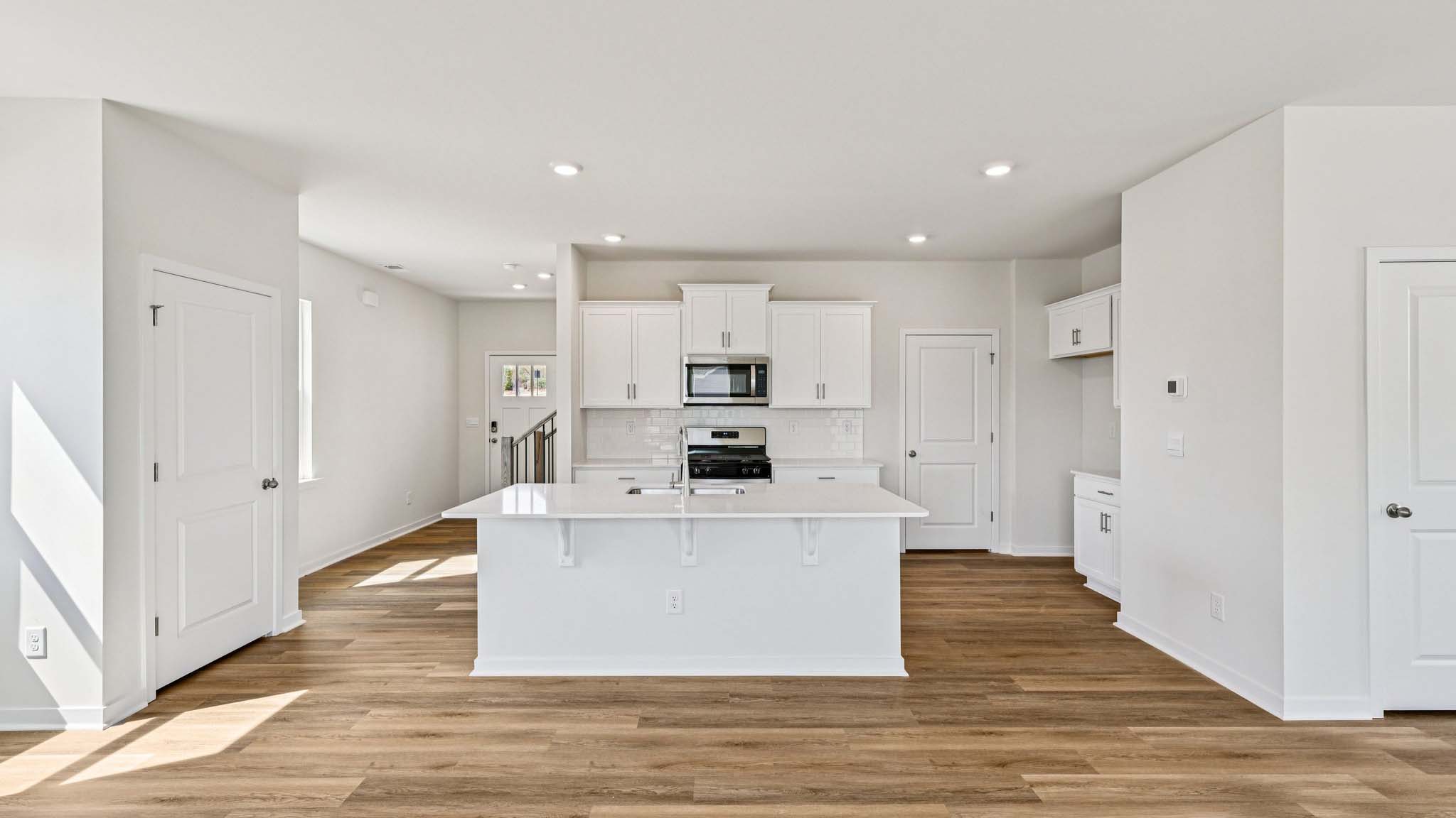 Kitchen and island with white cabinets, white subway tile backsplash and stainless steel appliances