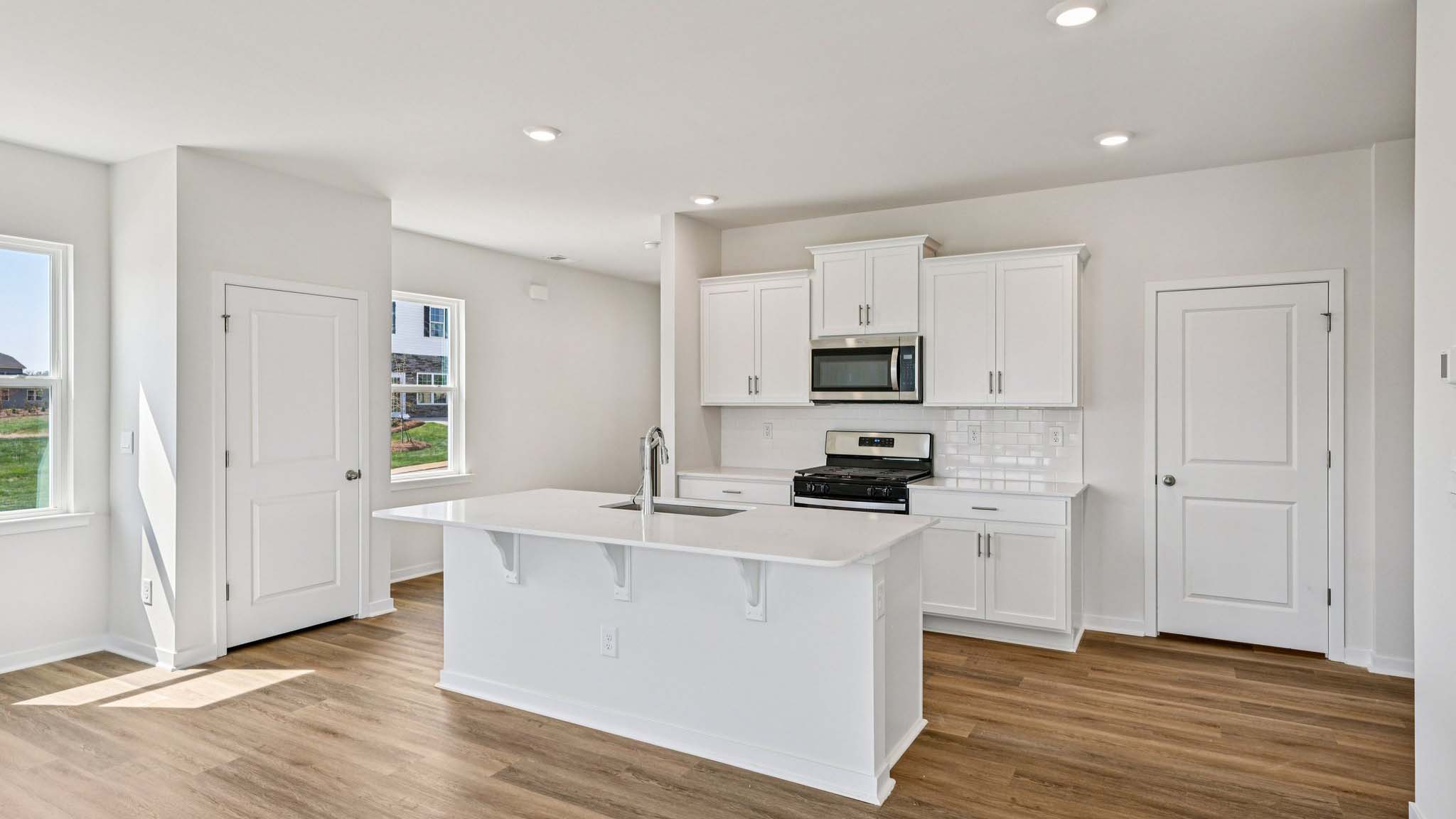 Kitchen and island with white cabinets, white subway tile backsplash and stainless steel appliances