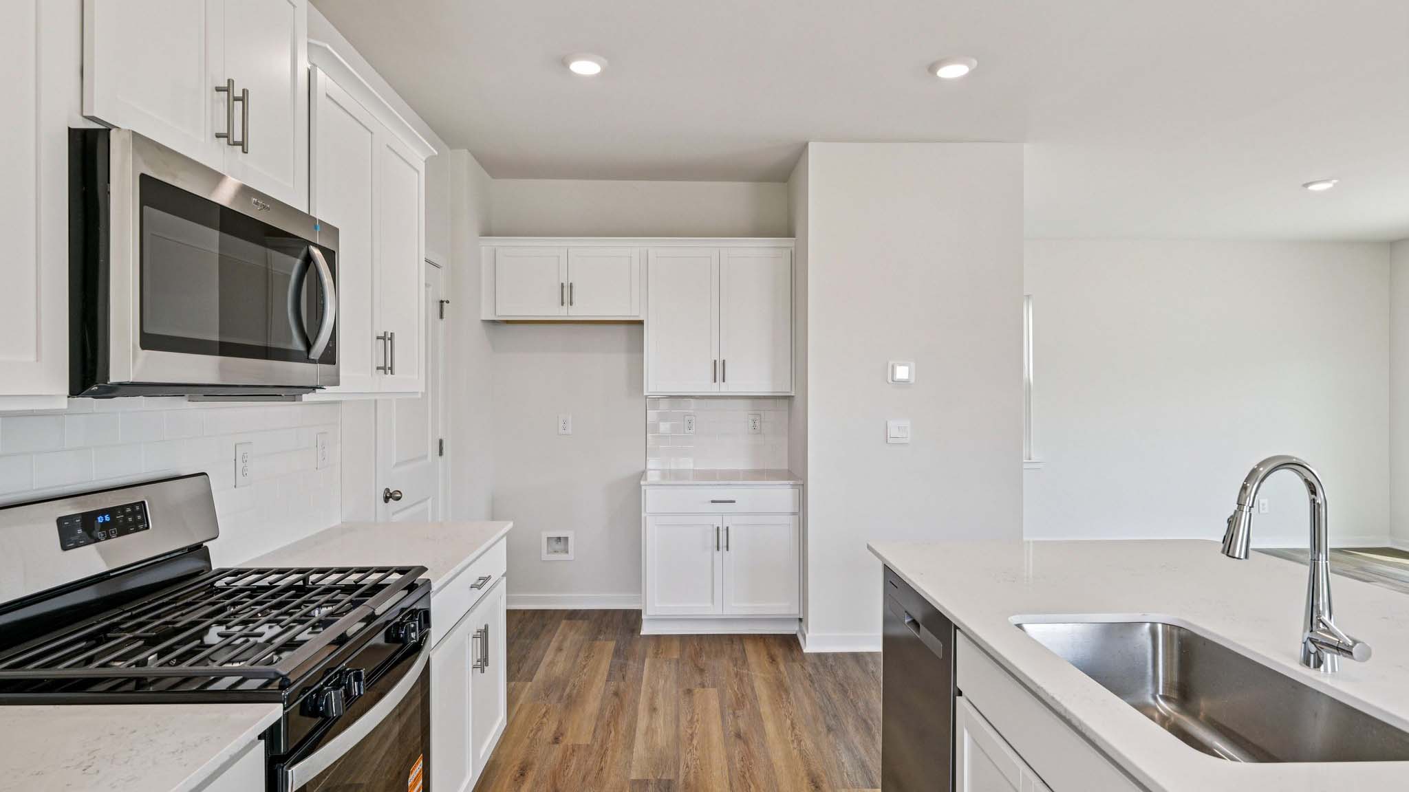 Kitchen and island with white cabinets, white subway tile backsplash and stainless steel appliances