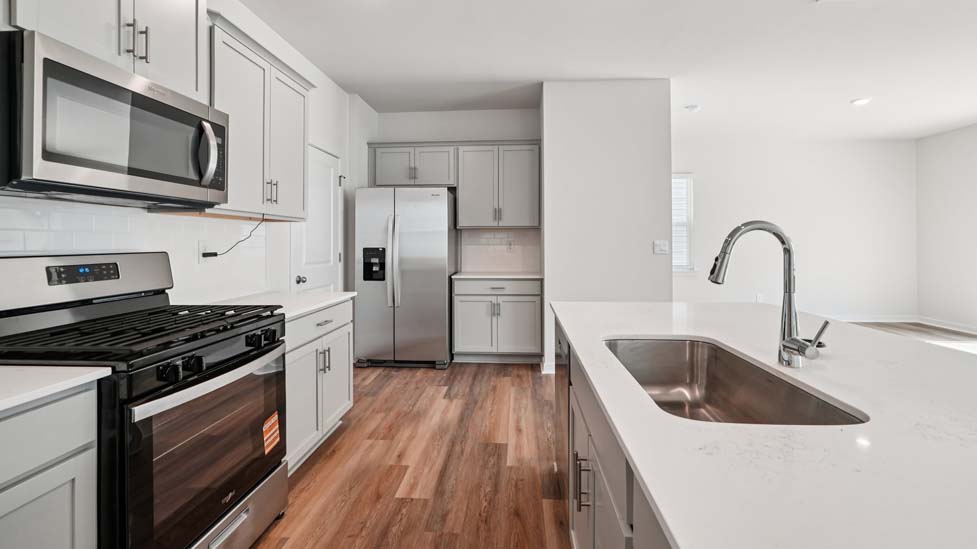 Kitchen and island with white cabinets, white subway tile backsplash and stainless steel appliances