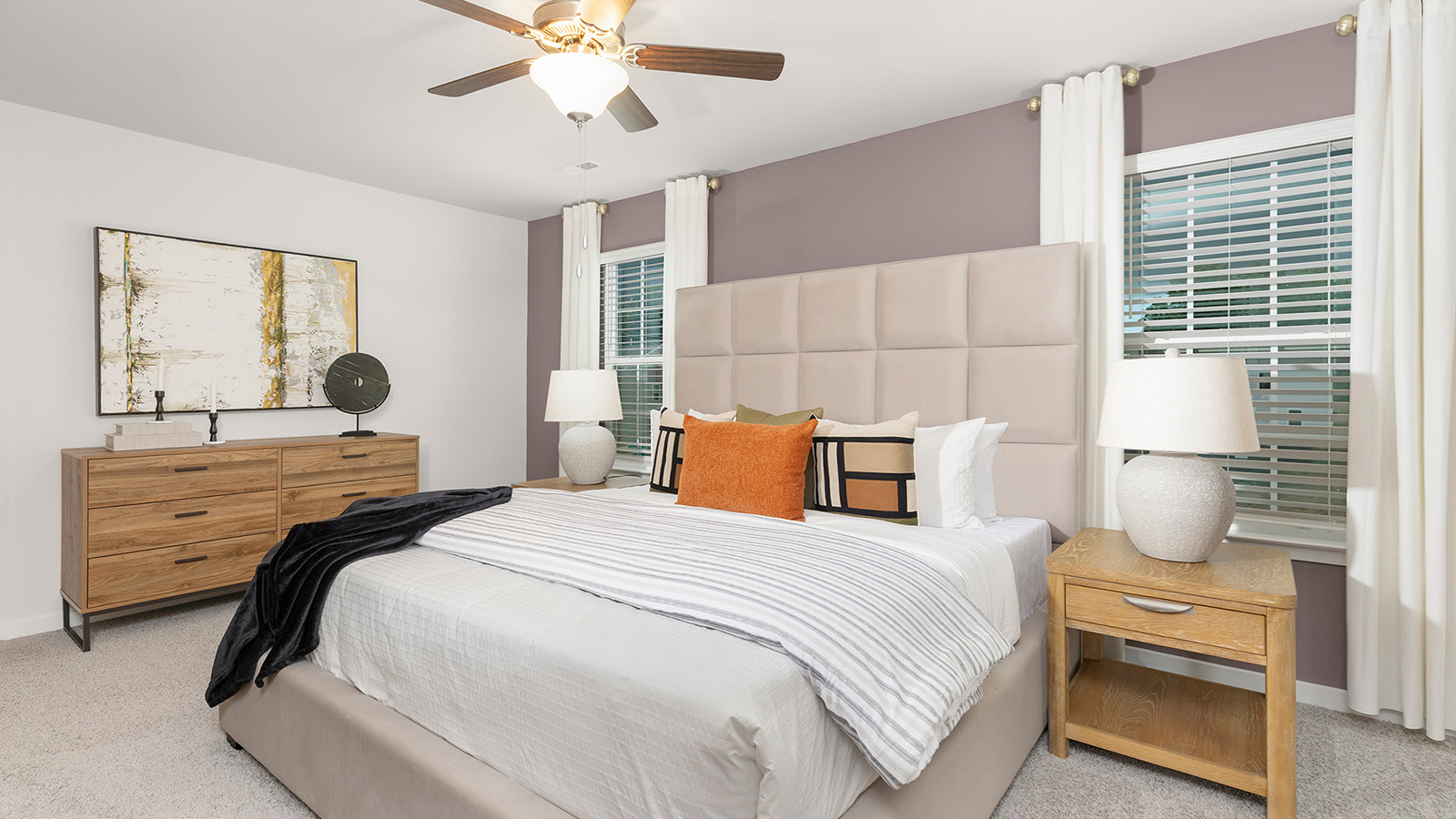 Primary bedroom with beige carpet and two large windows