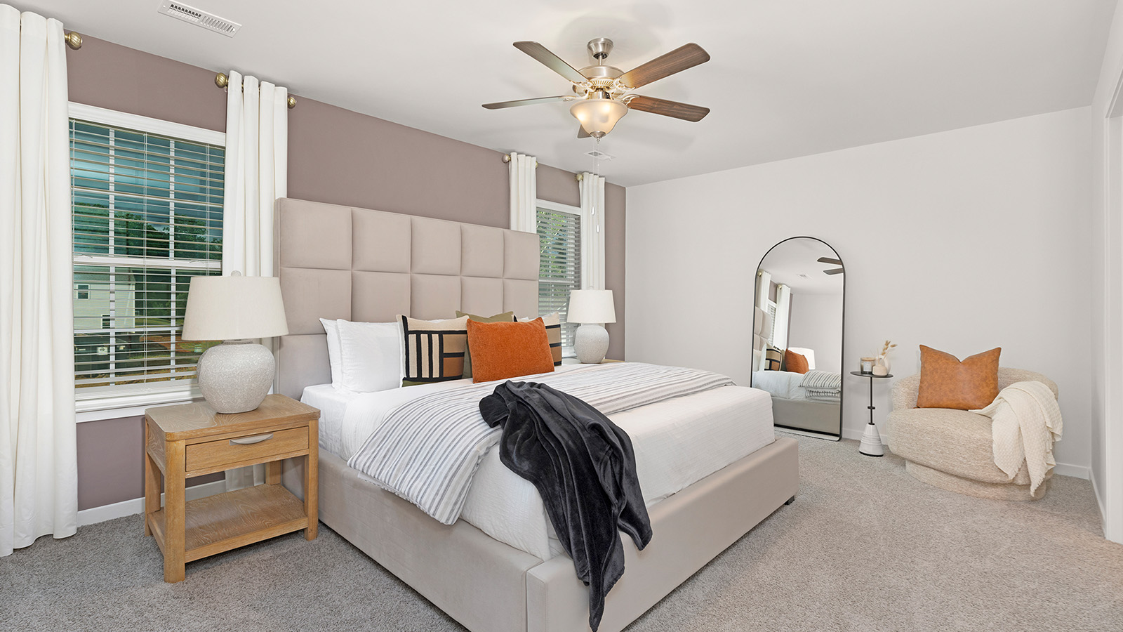 Primary bedroom with beige carpet and two large windows