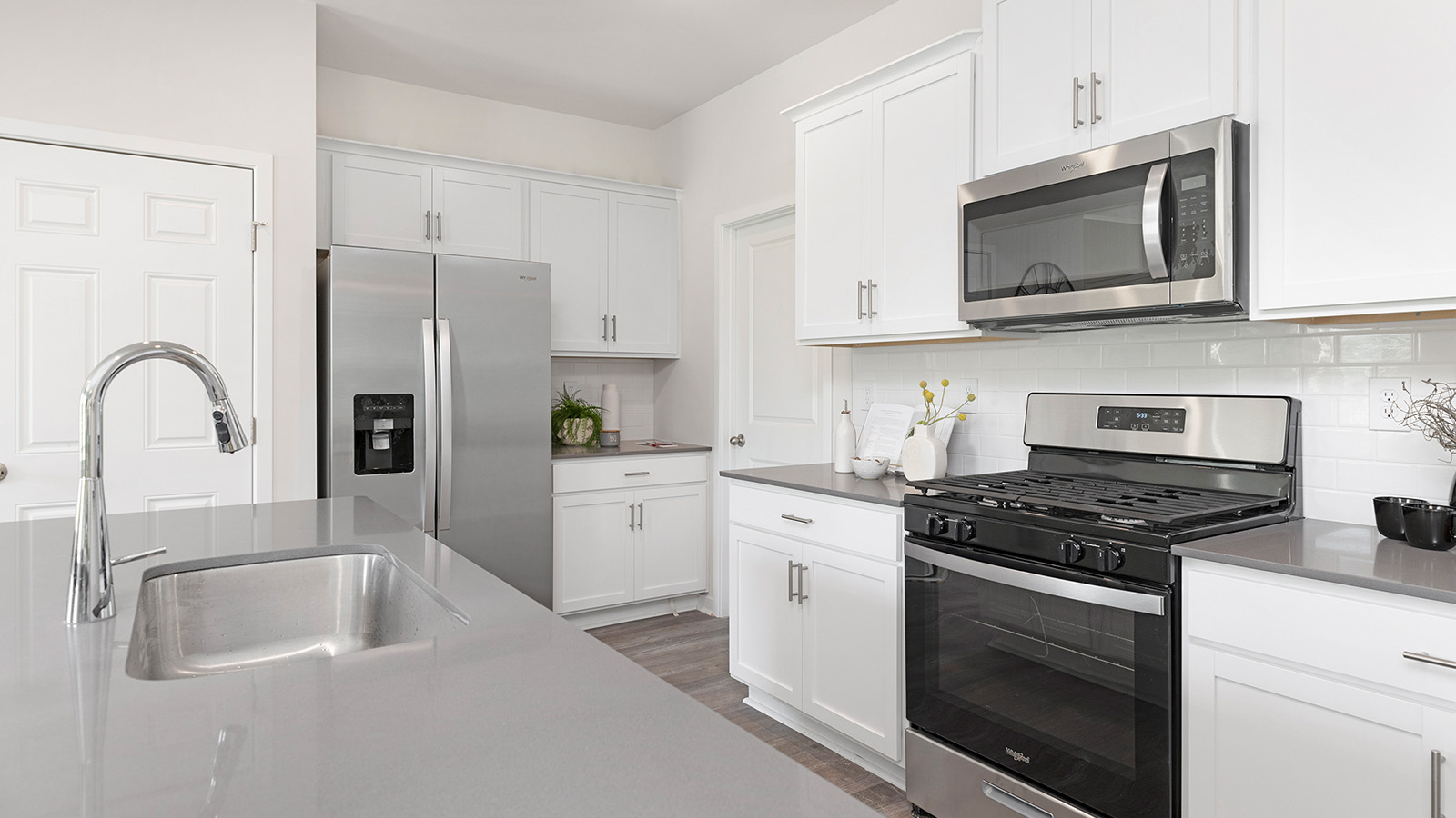 Kitchen and island with beige floors, white cabinets, white counters, and stainless steel appliances