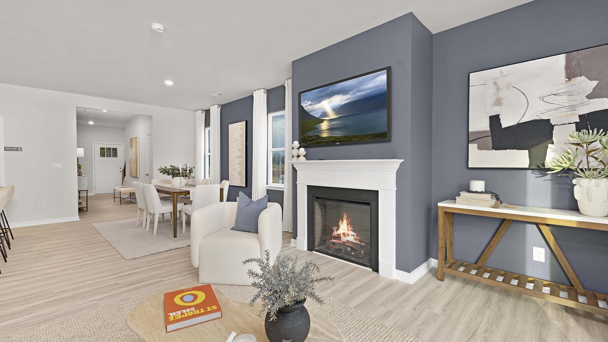 Open living room beside kitchen and dining room with direplace and large windows