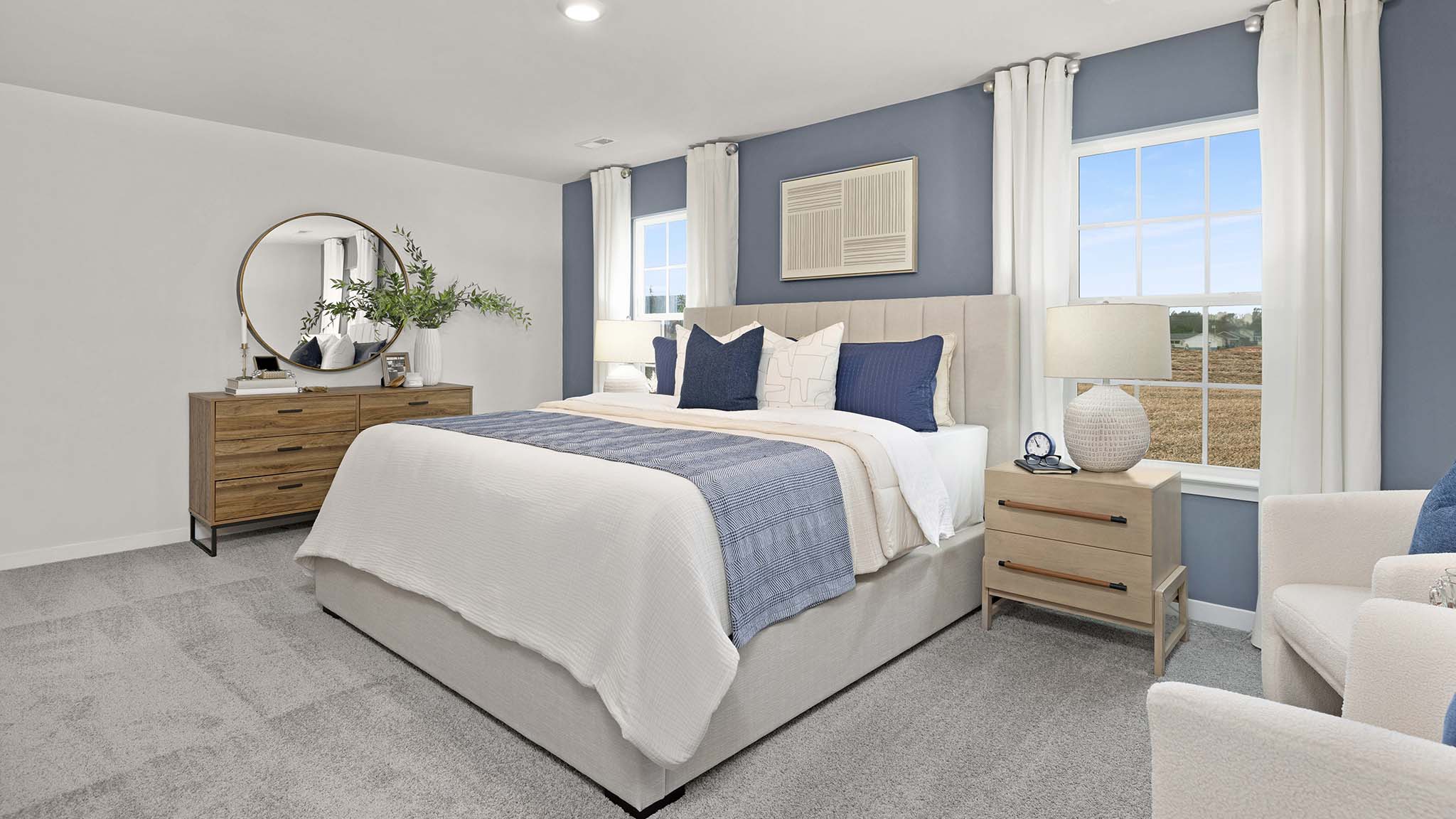 Primary bedroom with beige carpet and two large windows