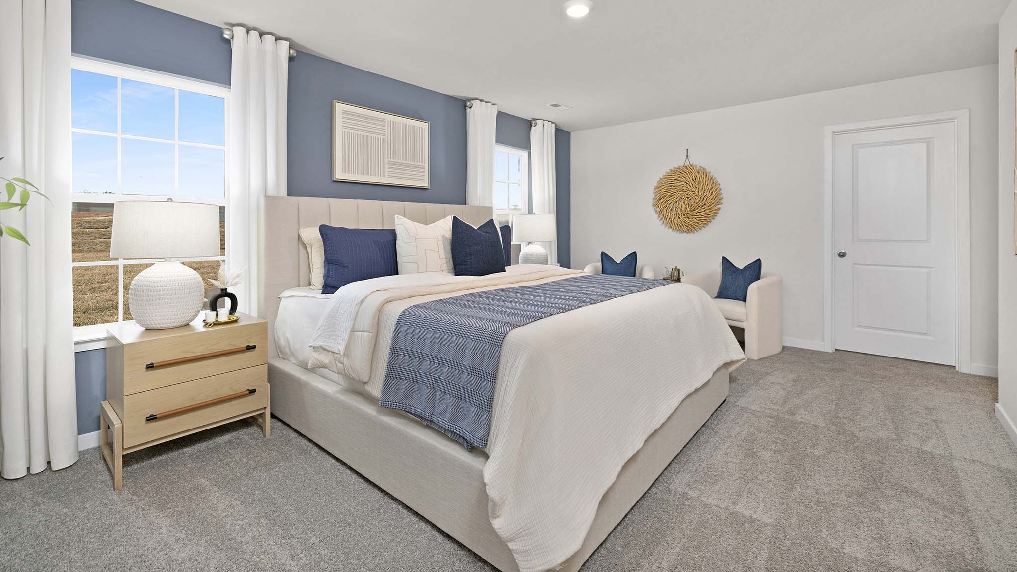 Primary bedroom with beige carpet and two large windows