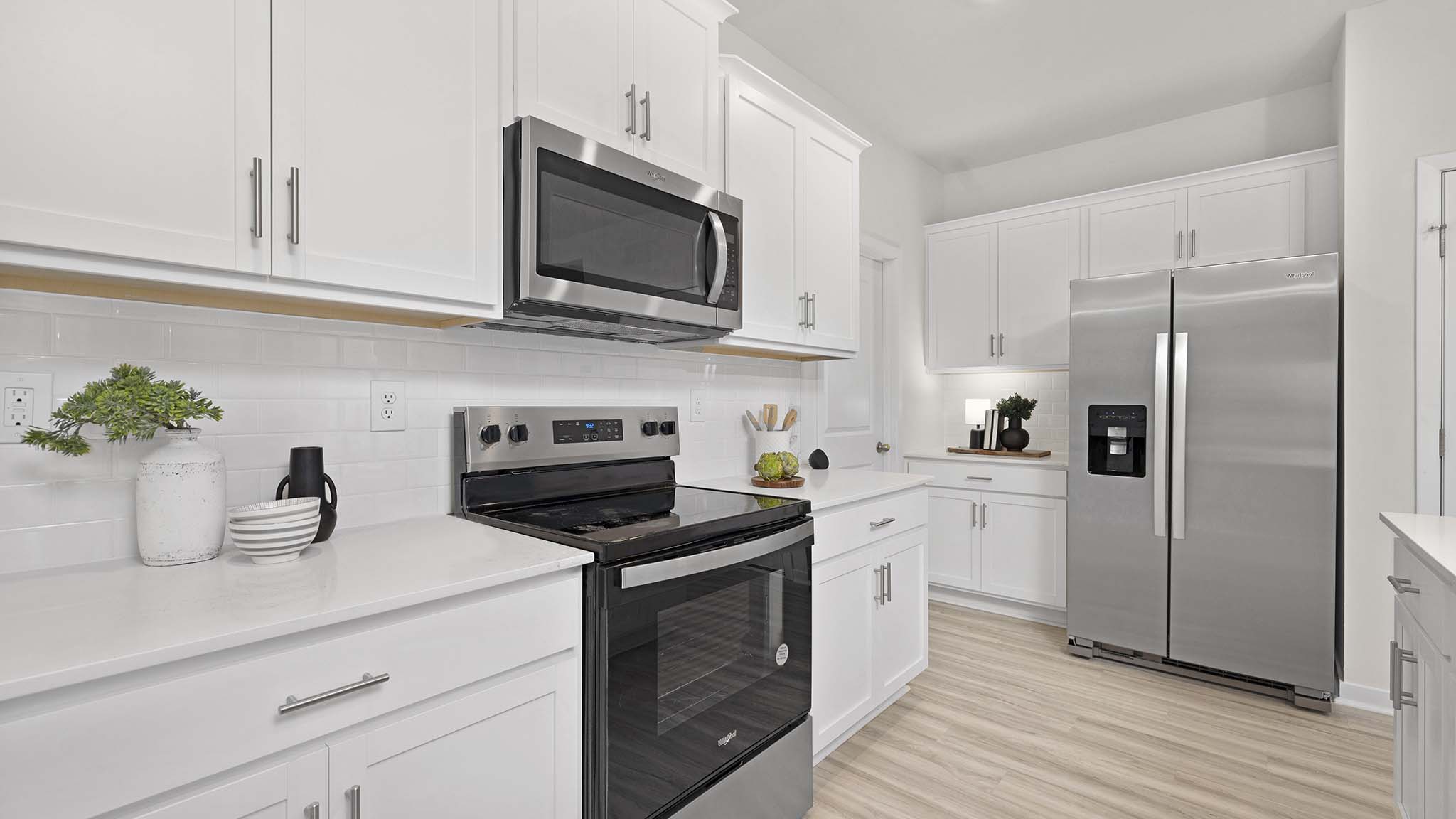 Kitchen and island with beige floors, white cabinets, white counters, and stainless steel appliances