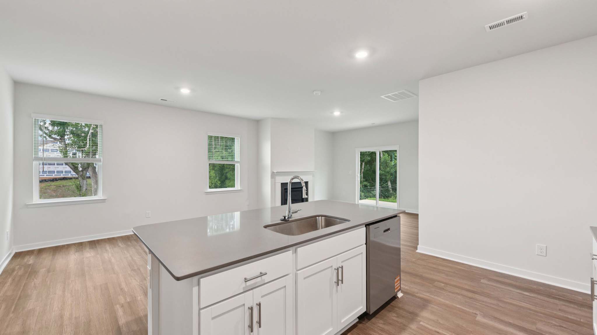 Kitchen and island with beige floors, white cabinets, white counters, and stainless steel appliances
