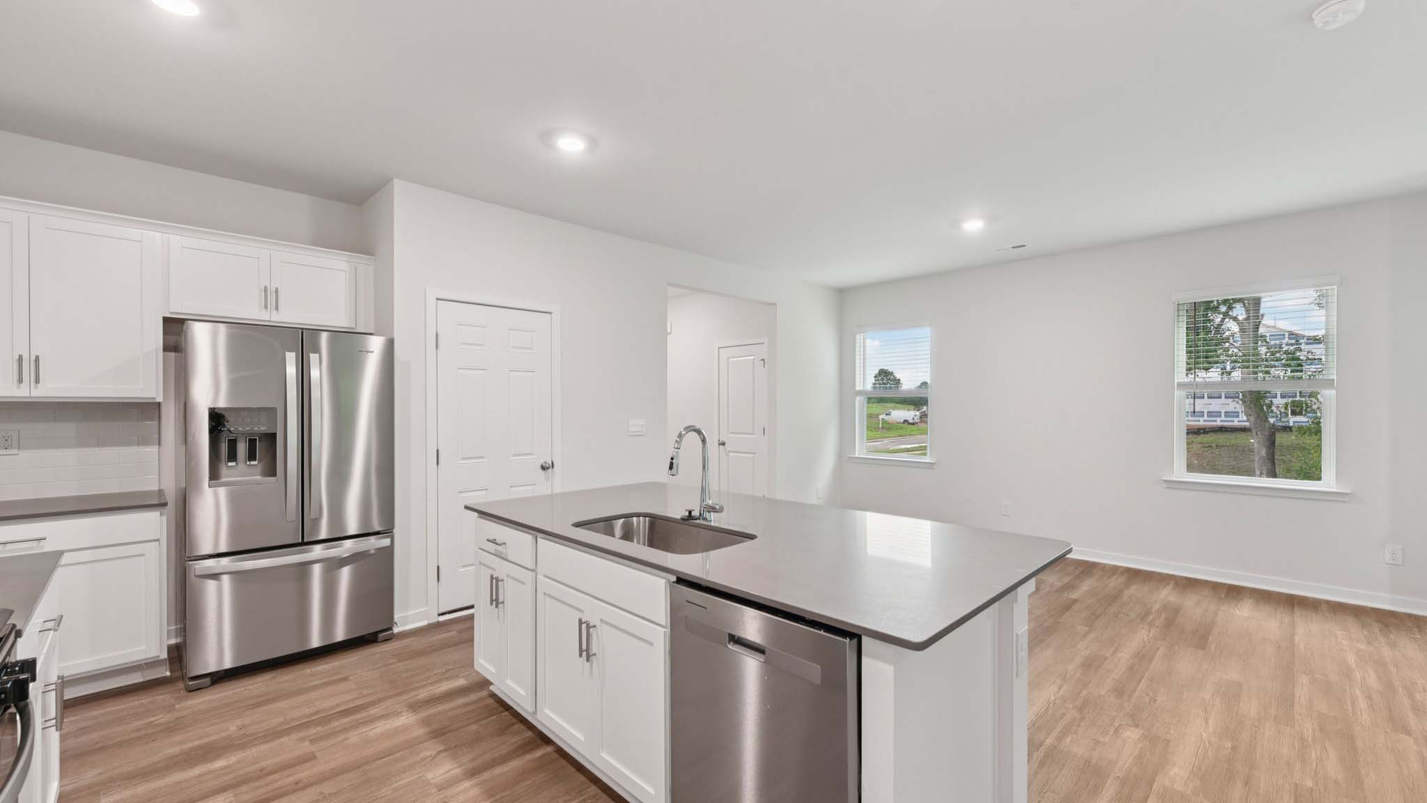 Kitchen and island with beige floors, white cabinets, white counters, and stainless steel appliances