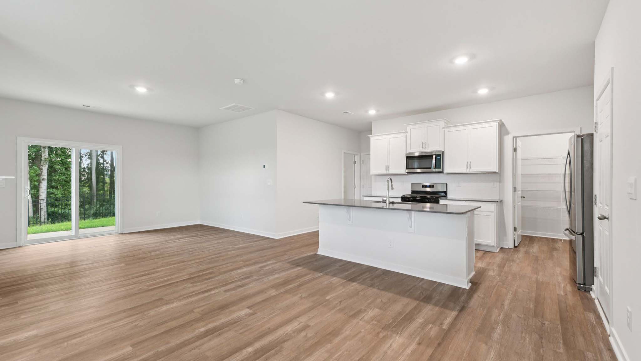 Kitchen and island with beige floors, white cabinets, white counters, and stainless steel appliances