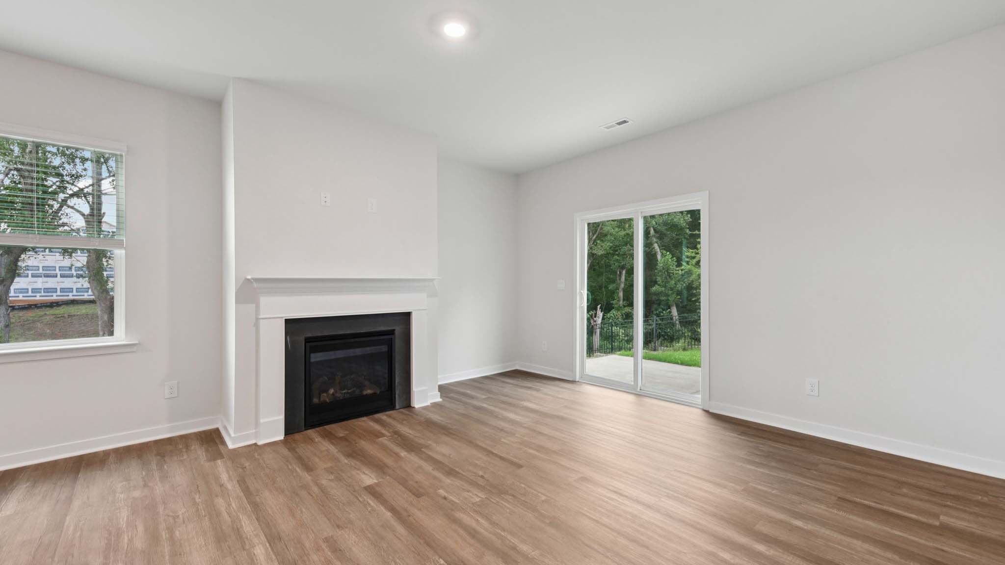 Open living room beside kitchen and dining room with direplace and large windows