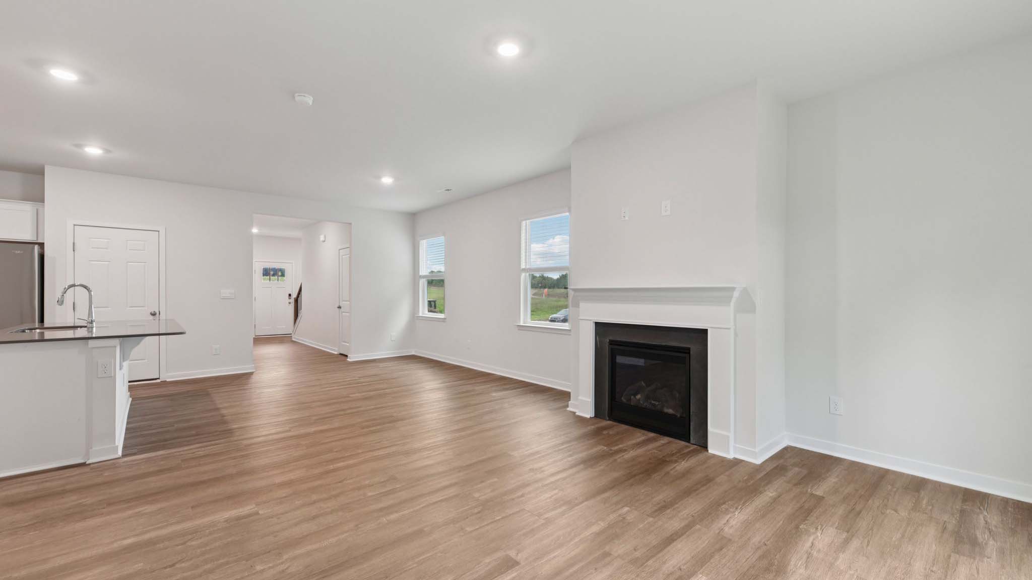 Open living room beside kitchen and dining room with direplace and large windows