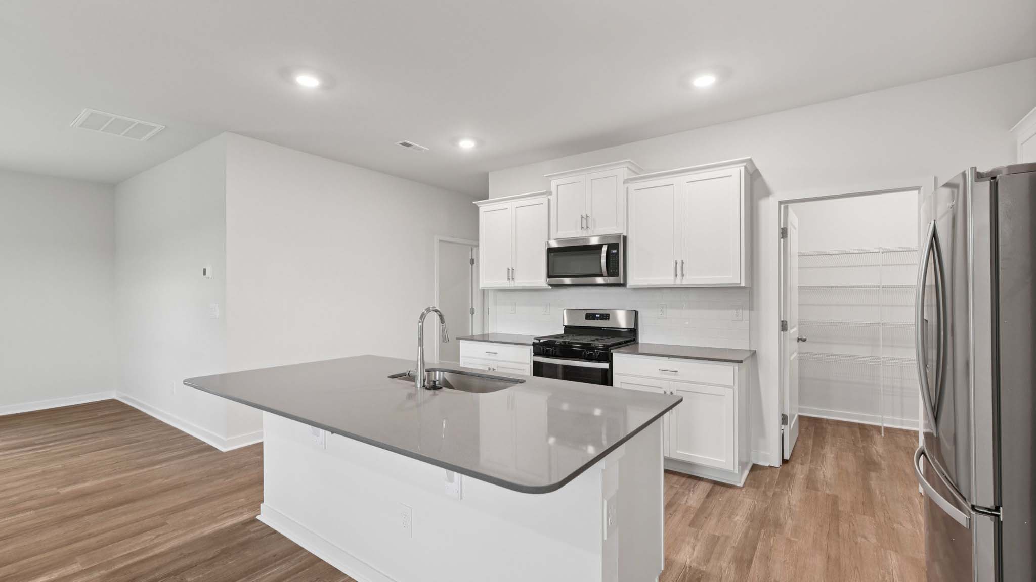 Kitchen and island with beige floors, white cabinets, white counters, and stainless steel appliances