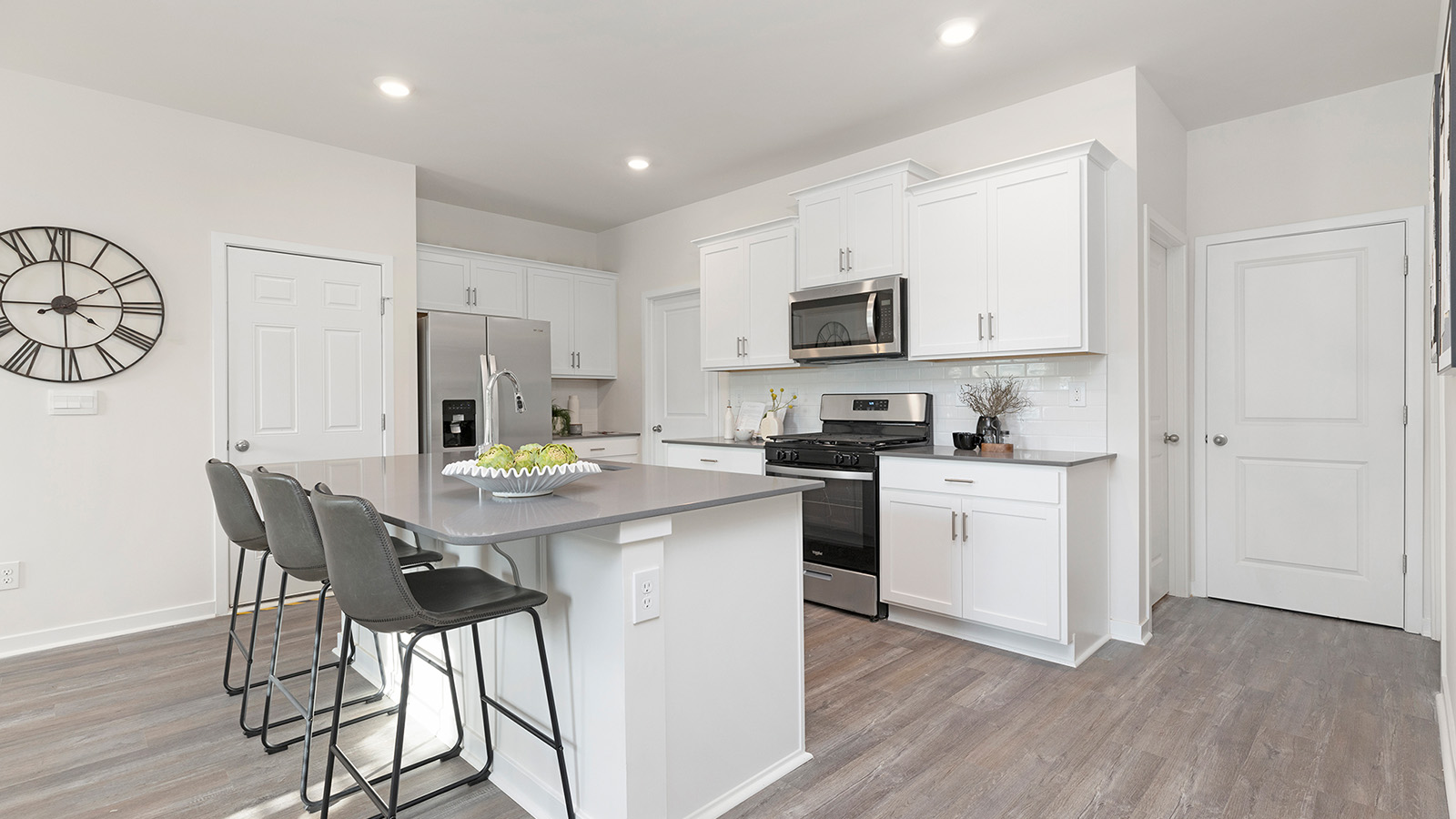 Kitchen and island with beige floors, white cabinets, white counters, and stainless steel appliances