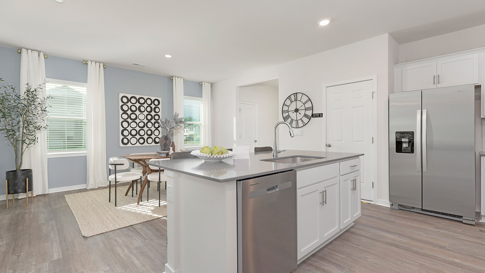 Kitchen and island with beige floors, white cabinets, white counters, and stainless steel appliances