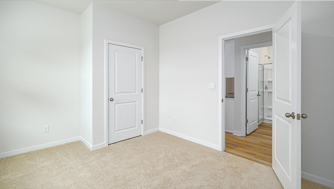 carpeted bedroom with small window and closet