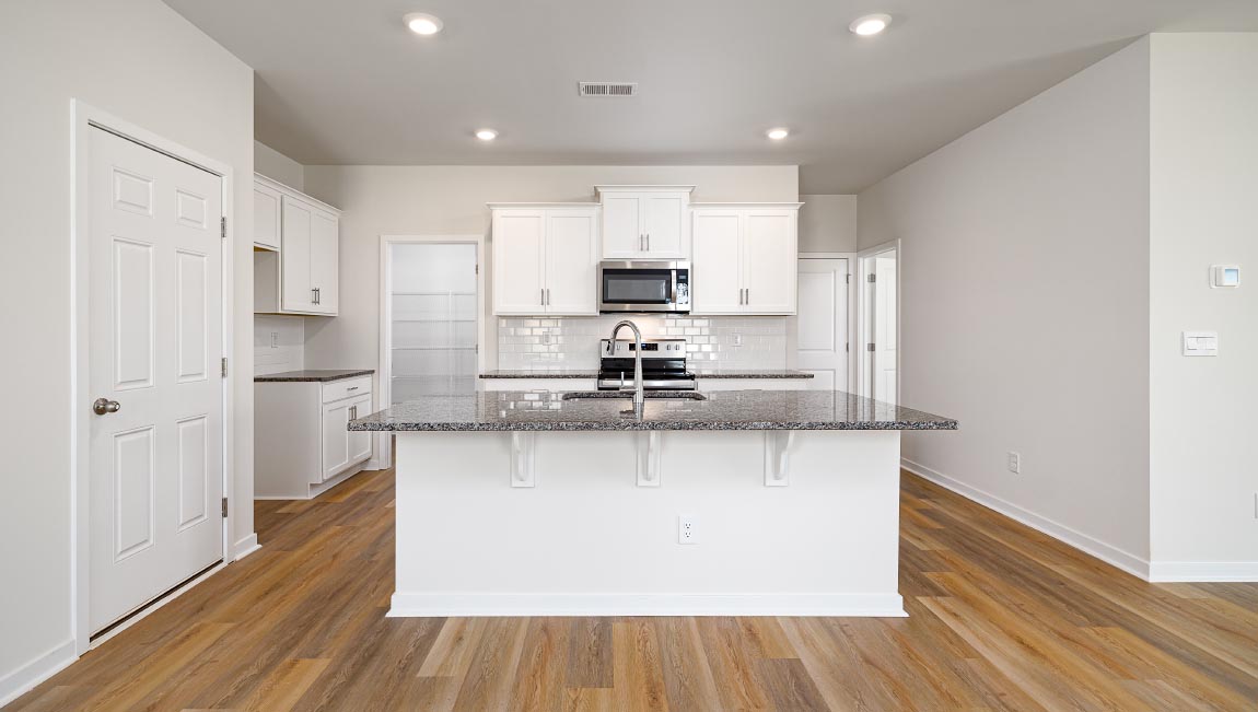 Kitchen and island with subway tile backsplash, quartz countertops, white cabinets and stainless steel appliances