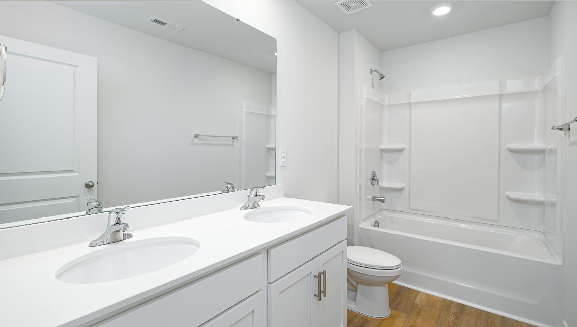 Bathroom with double sink vanity, white cabinets and bathtub shower combination