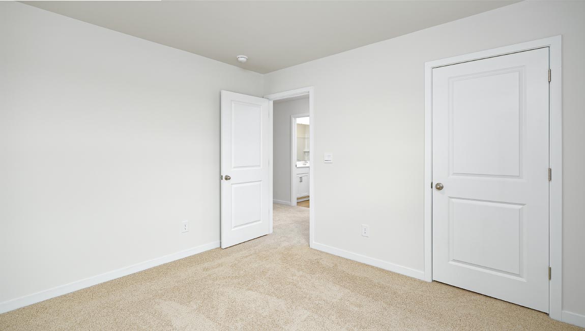 carpeted bedroom with small window and closet