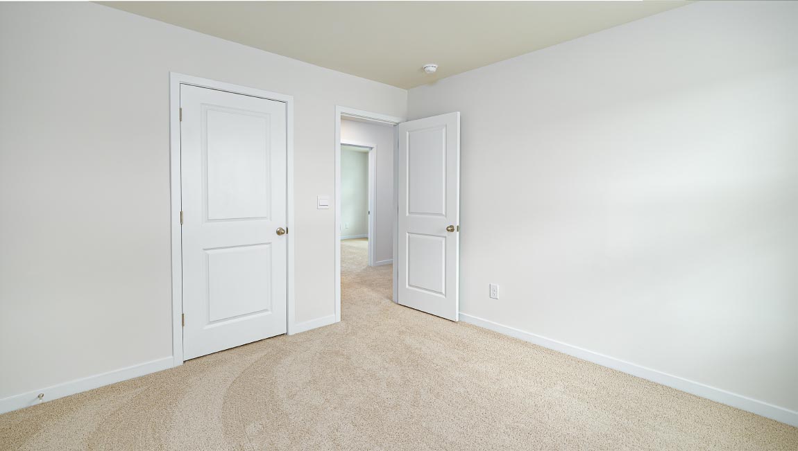 carpeted bedroom with small window and closet