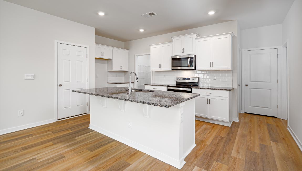 Kitchen and island with subway tile backsplash, quartz countertops, white cabinets and stainless steel appliances