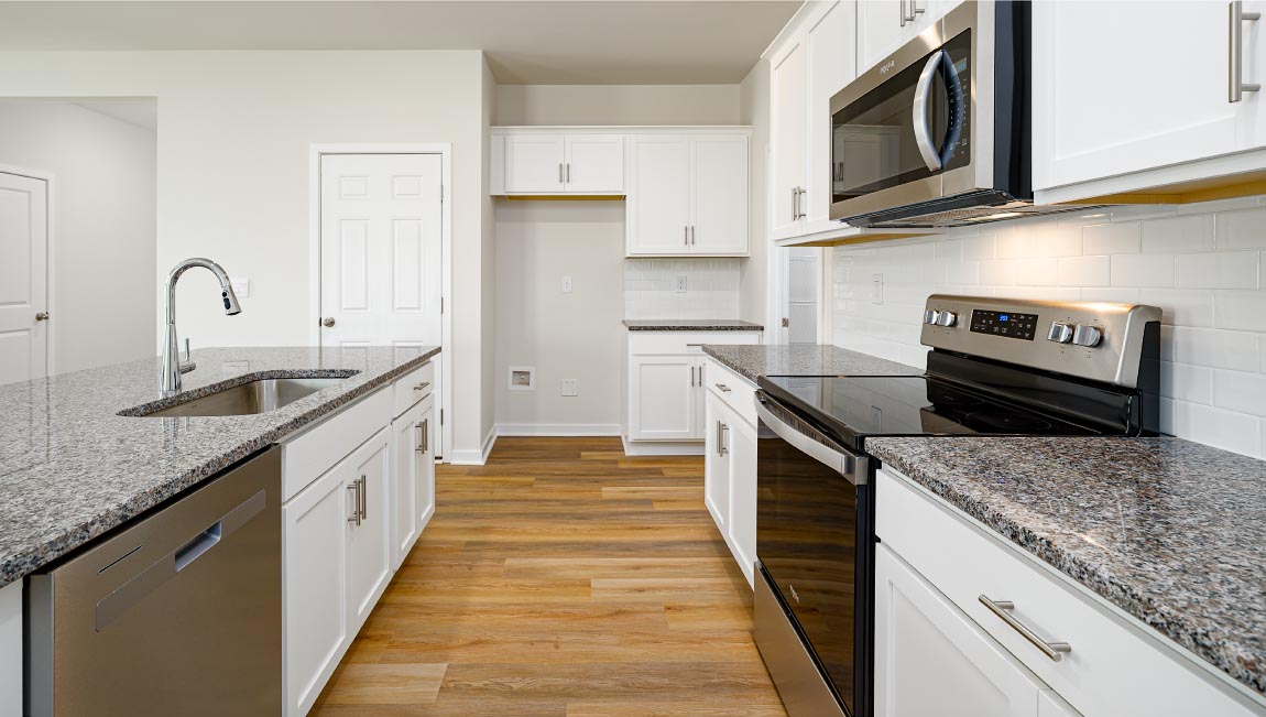 Kitchen and island with subway tile backsplash, quartz countertops, white cabinets and stainless steel appliances
