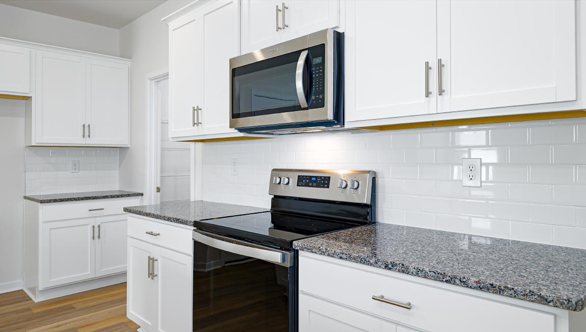 Kitchen and island with subway tile backsplash, quartz countertops, white cabinets and stainless steel appliances
