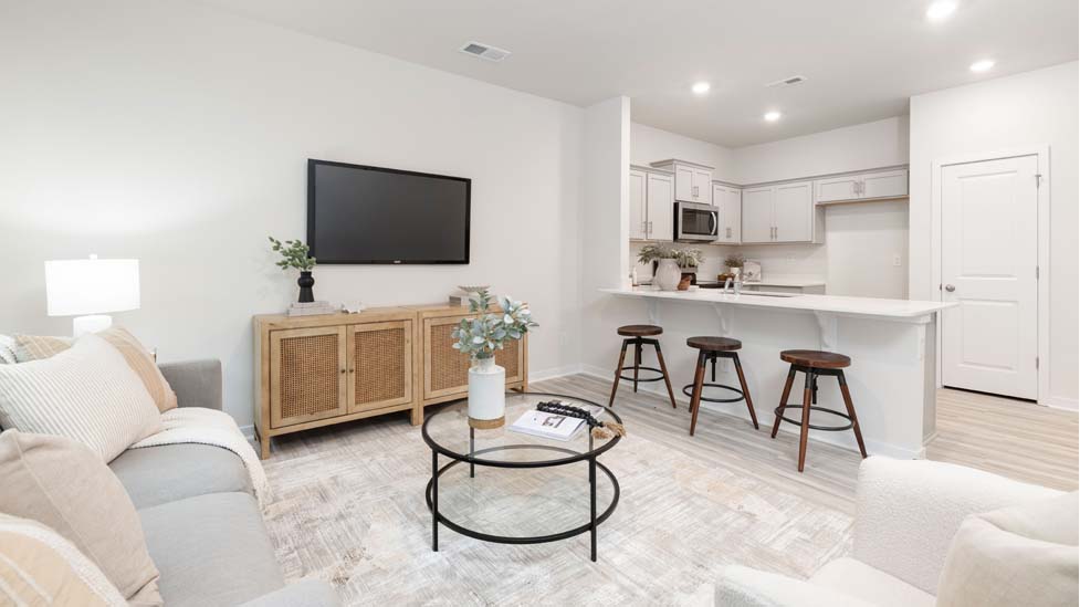 Open living room beside kitchen and dining room with direplace and large windows