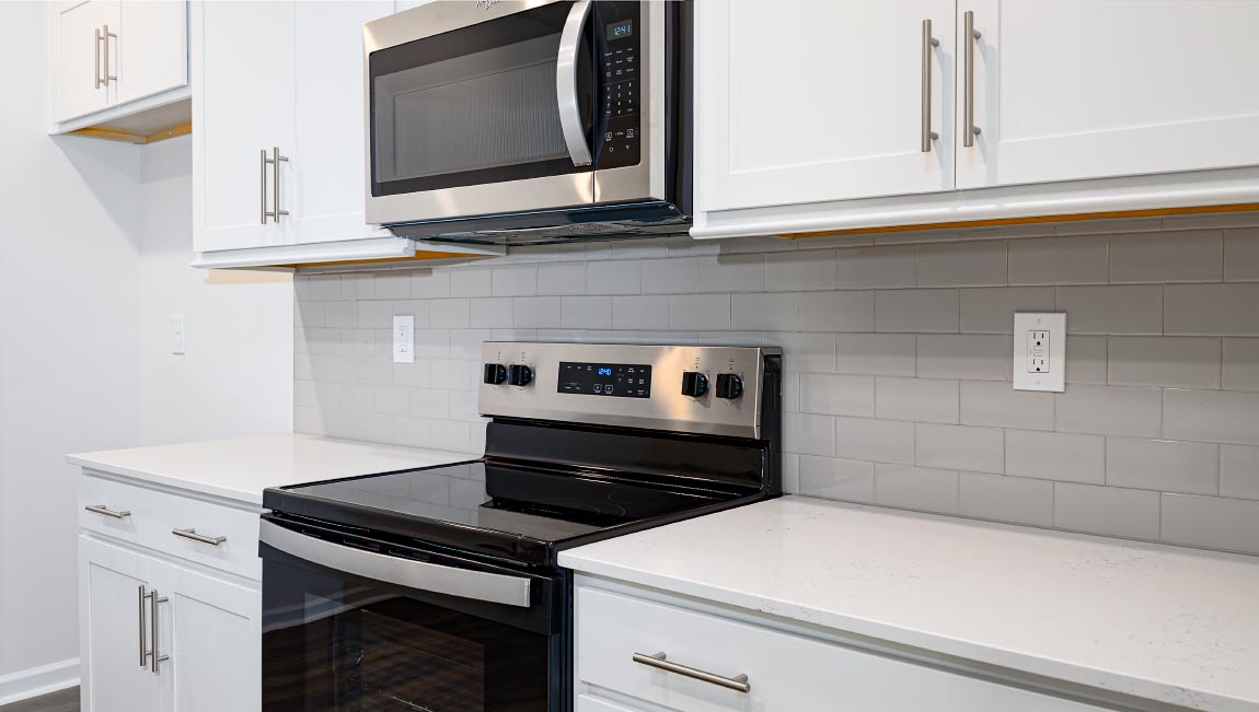 Kitchen and island with white cabinets and subway tiles and stainless steel subway tiles