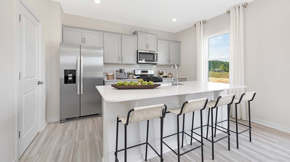 Kitchen and island with white cabinets and counters, vinyl floors and stainless steel appliances