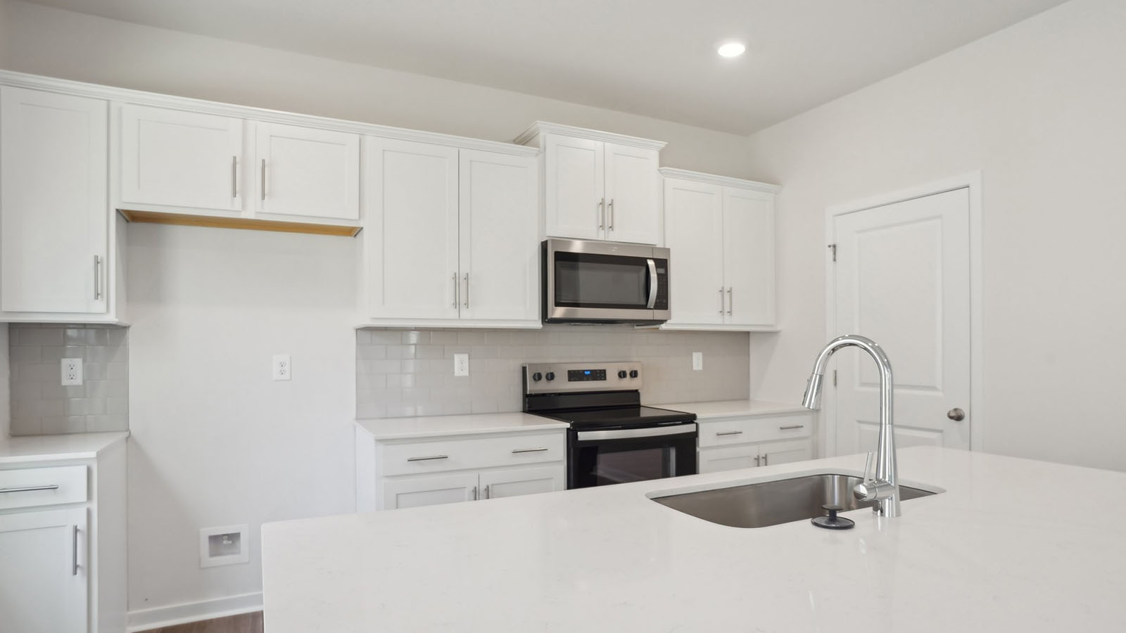 kitchen and island with white cabinets, wood floors and stainless steel appliances