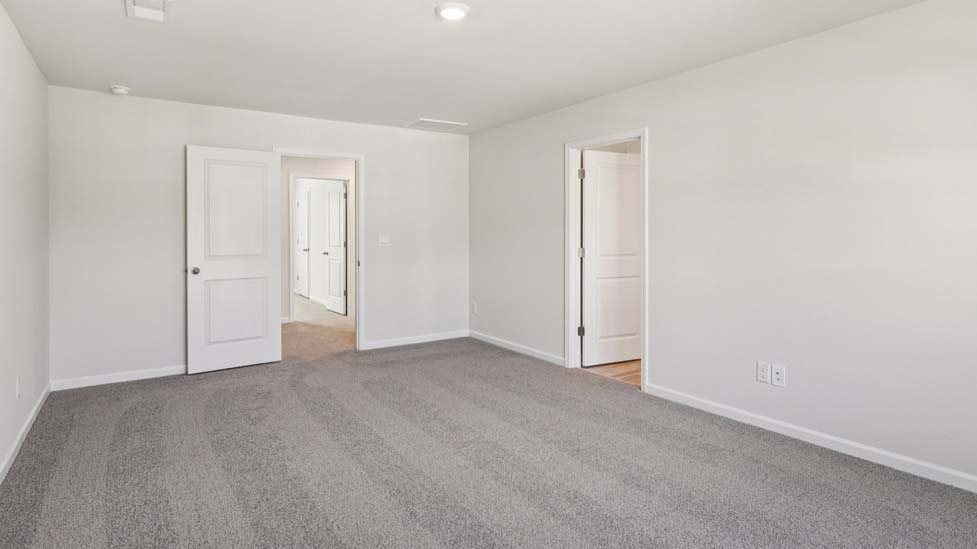 Primary carpeted bedroom with windows