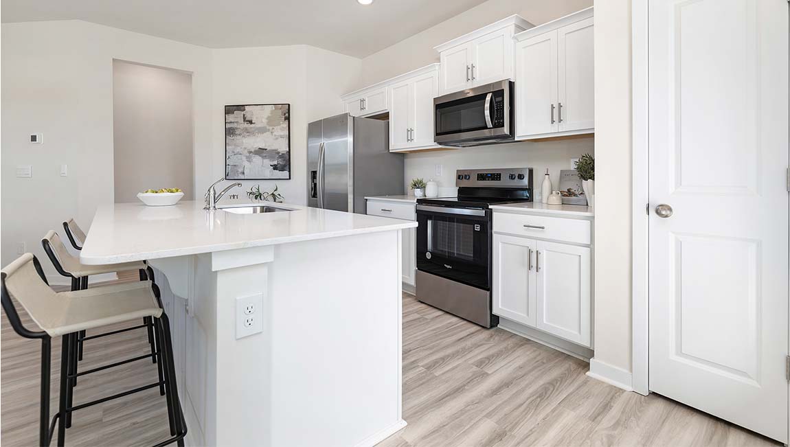 Kitchen and island with white cabinets, subway tile backsplash, and stainless steel appliances