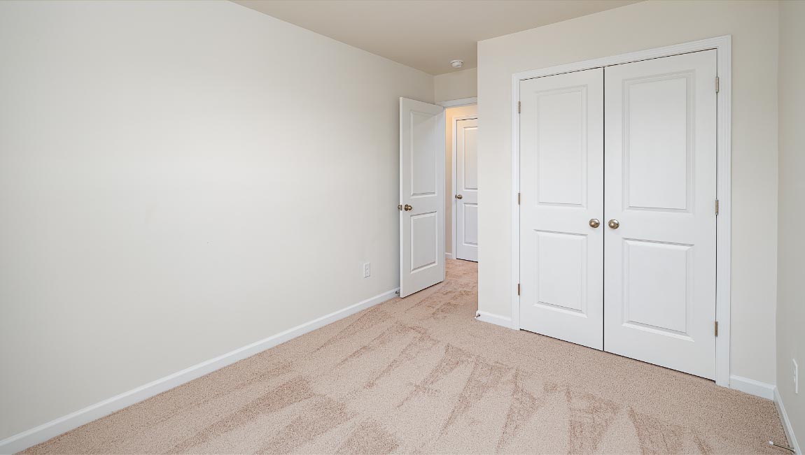 Carpeted bedroom with view of entryway and closet doors
