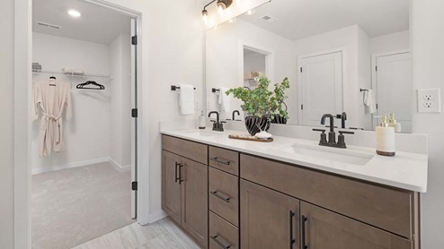 Primary bathroom with double sink vanity and walkway into closer