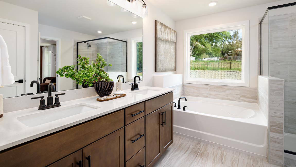 Primary bathroom with double sinks and standing glass shower with tub