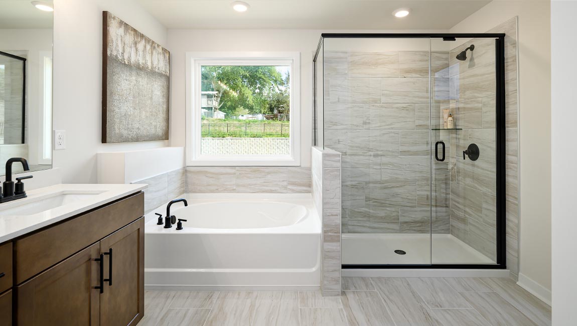 Primary bathroom with double sinks and standing glass shower with tub