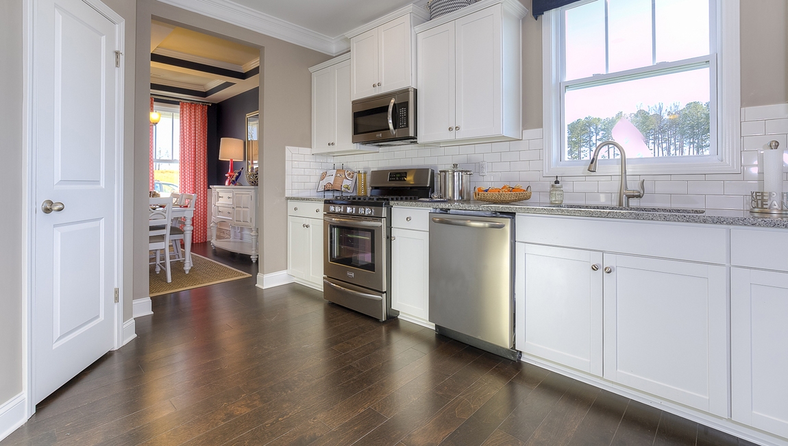 Kitchen and island with white cabinets, breakfast area at island bar, and stainless steel appliances