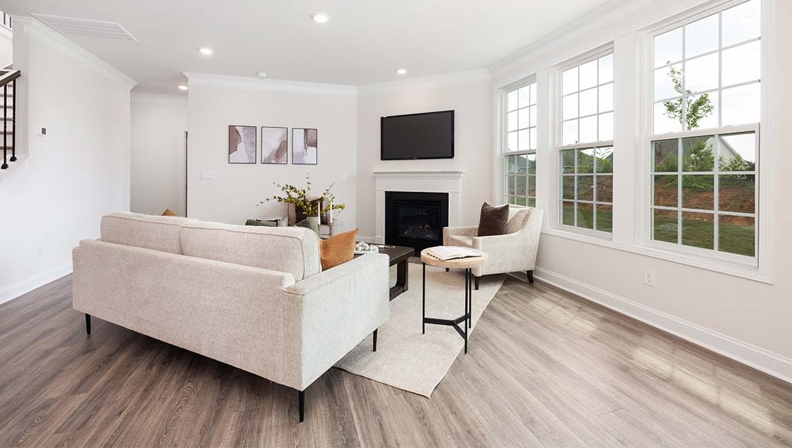 Living room space beside kitchen with wood floors and fireplace