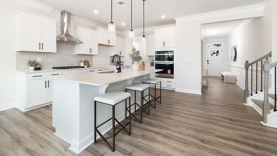 Kitchen and island with white cabinets and counters, wood floors, and stainless steel appliances