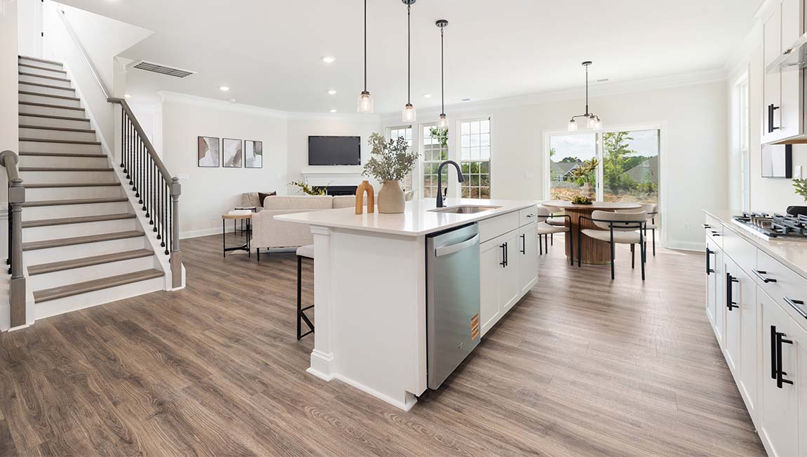 Kitchen and island with white cabinets and counters, wood floors, and stainless steel appliances