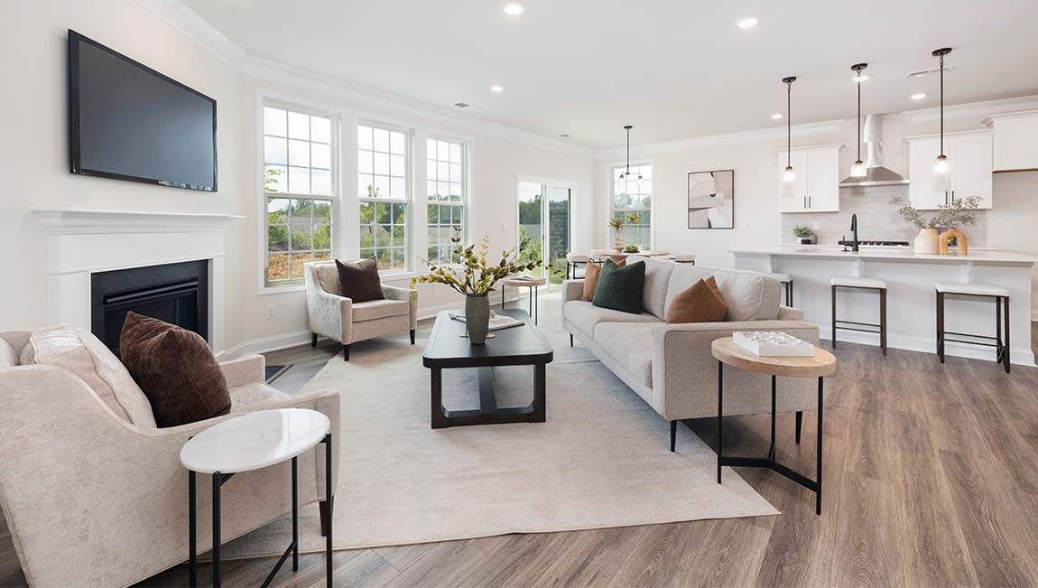Living room space beside kitchen with wood floors and fireplace