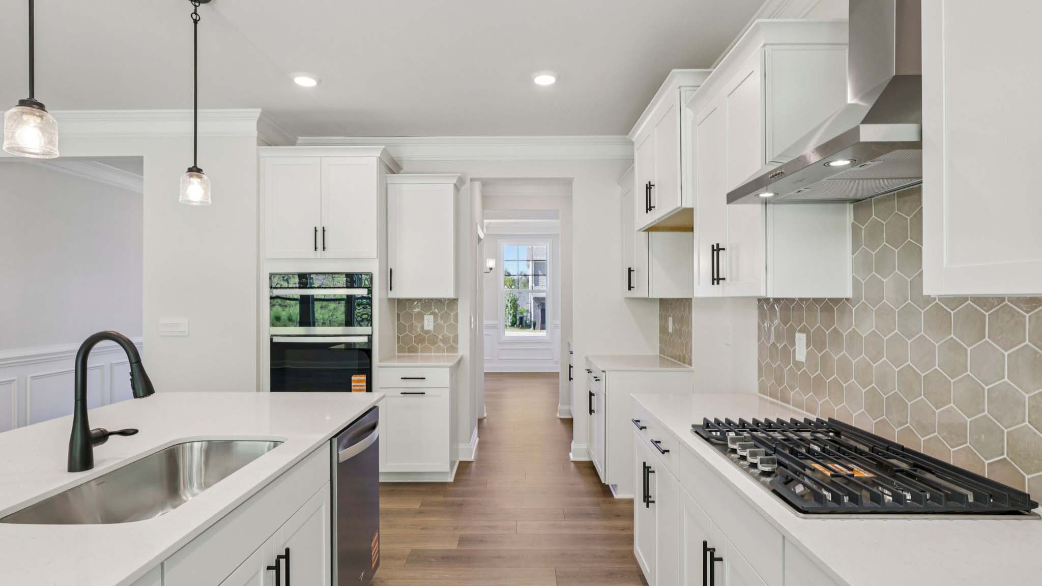 Kitchen and island with white cabinets and counters, wood floors, and stainless steel appliances