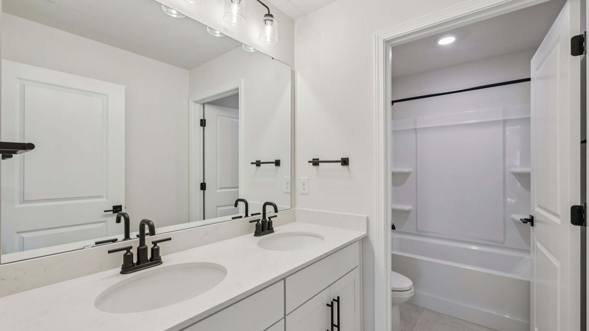 Bathroom with double sinks, white cabinets and counters