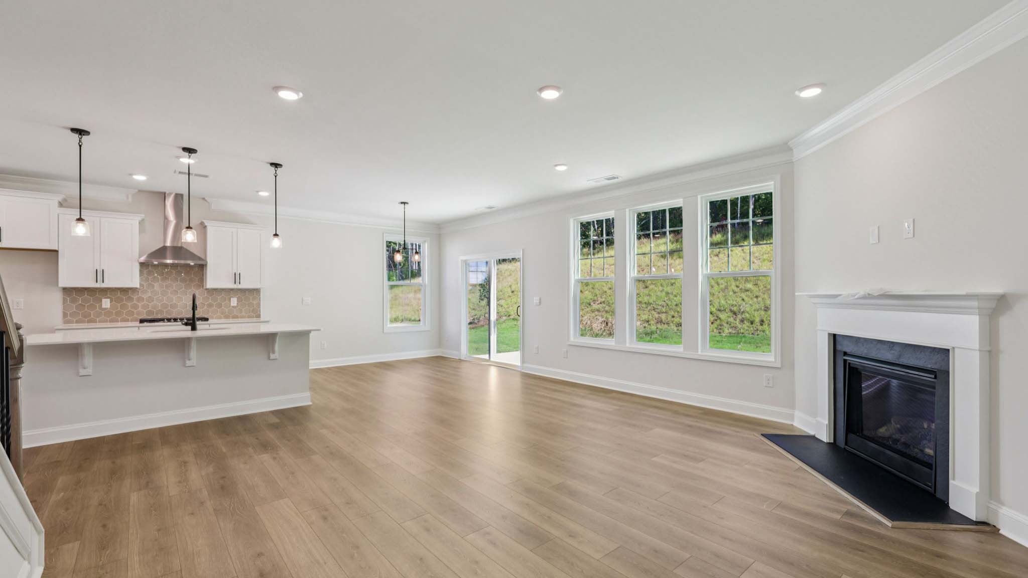 Living room space beside kitchen with wood floors and fireplace